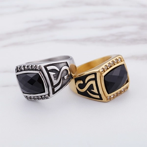 Detailed close-up of hip hop style rings with black stones and engraved silver and gold bands