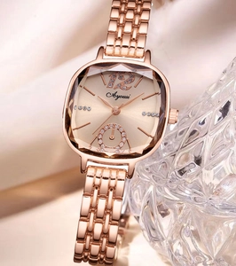 Gros plan d'une montre carrée en or rose avec cadran en strass sur satin soyeux