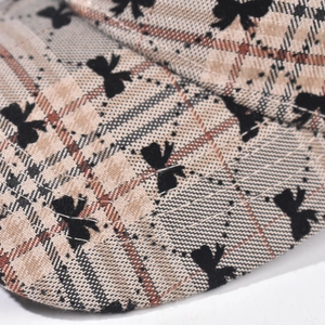 Macro shot of plaid baseball cap fabric with black bow patterns and detailed stitching