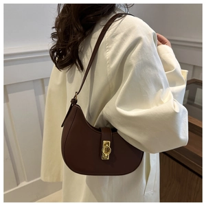 Detail der dunkelbraunen Halbmond-Satteltasche mit goldenem Verschluss am Model im Trenchcoat
