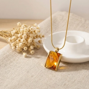 Detailed view of amber square gemstone pendant on 18K gold-plated snake chain necklace