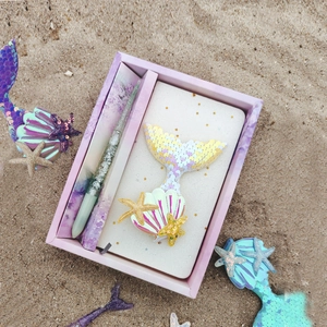 Mermaid stationery set with sequin notebook and pen on beach background