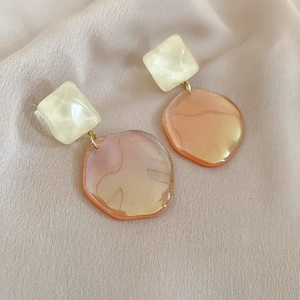 Detail shot of vintage resin earrings with cream squares and orange gradient pendants