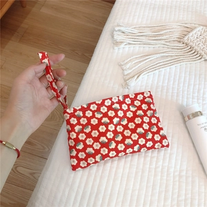 Close-up of red floral cotton phone bag with daisy patterns and wristlet strap