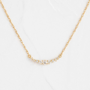 Minimalist gold smile necklace featuring nine graduated cubic zirconia stones on thin chain