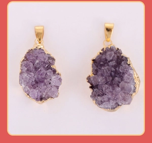 Detail of natural raw amethyst crystal pendants with elegant gold plated metal edges