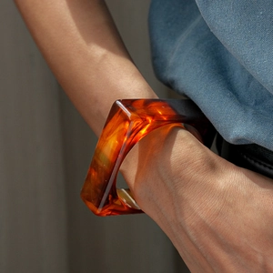 Detail view of amber resin geometric bangle showing unique texture and light transparency