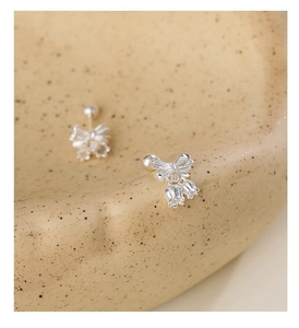 Macro detail of silver bow and lily of the valley earrings with screw back on ceramic