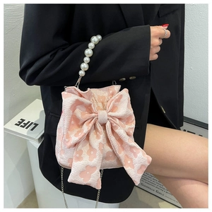 Detail of pink floral embossed handbag with large bow and white pearl handle