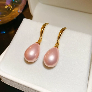 Détail de boucles d'oreilles perles roses en forme de goutte dans un écrin en velours blanc