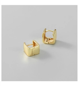Macro detail of polished gold square huggie earrings with a modern minimalist texture