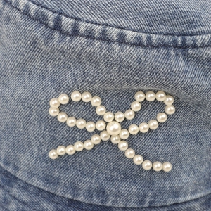 Détail du nœud en perles blanches sur le chapeau bob en denim bleu délavé