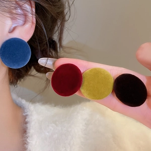 Detail of four velvet button earrings in blue, burgundy, yellow and black colors
