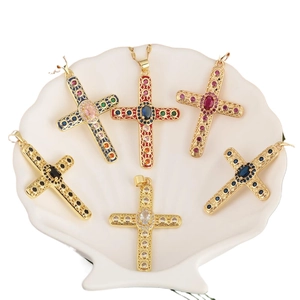 Six pendentifs croix dorés avec zircons colorés présentés dans un plateau blanc