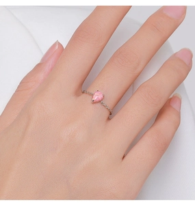 Detail of sterling silver chain ring with a teardrop pink opal on a female finger