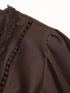 Dettaglio dell'abito marrone scuro con scollo a V, pizzo raffinato e design traforato