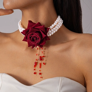 Détail d'un choker en perles à trois couches avec rose en velours bordeaux et glands