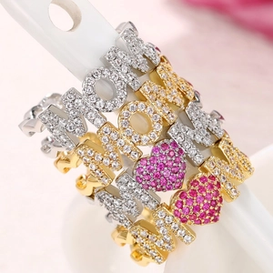 Detailed macro view of gold and silver MOM rings with pavé crystals and pink hearts