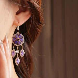 Detail of vintage gold tassel earrings with purple stones and zircon on model