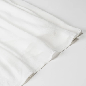 Détail de l'ourlet d'une robe en mousseline blanche avec coutures fines et texture