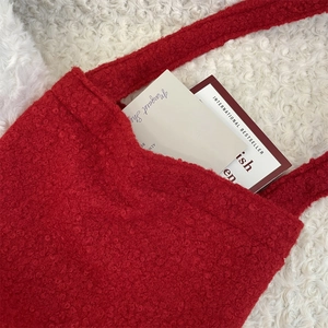 Gros plan d'un sac cabas rouge en peluche montrant la texture douce et la bandoulière