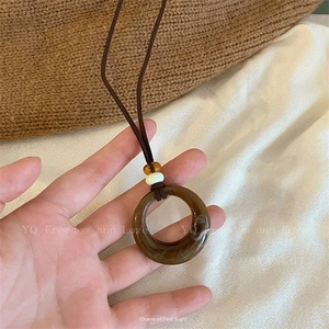 Détail du collier vintage à fleurs avec pendentif en résine marbrée et perles