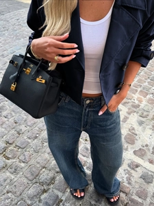 Detailansicht goldener Beschläge und Markenlogo auf einer schwarzen Lederhandtasche