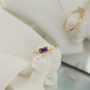 Close-up of 18K gold plated ring with purple rectangular gemstone on an artistic statue