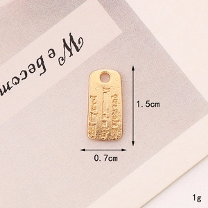 Macro detail of a golden zinc alloy rectangular pendant with vintage hammered texture