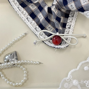 Detail of navy blue plaid scrunchie with lace edge and deep red bead decoration