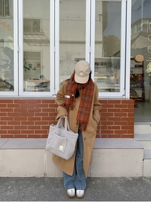 Macro shot of grey faux shearling tote bag styled with long khaki coat and red scarf
