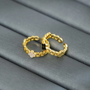 Detailed view of adjustable gold-plated clover rings with black and white flower inlay