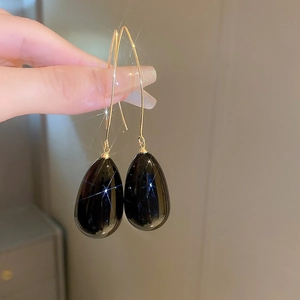 Gros plan de boucles d'oreilles perles gouttes noires avec crochets dorés et éclats