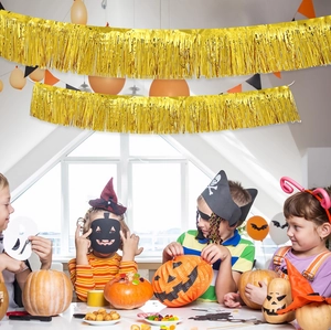 Guirlande à franges dorées suspendue au-dessus d'enfants fêtant Halloween dans un décor festif