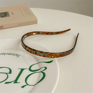 Detail of tortoise shell acetate headband with inner teeth on a white decorative plate