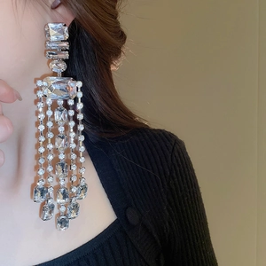 Close-up of dangling rhinestone tassel earrings with geometric crystal studs on a model