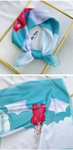 Detail of blue and white square silk scarf featuring a pink winged monster illustration