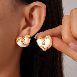Minimalist gold heart-shaped stud earrings with white enamel finish on model