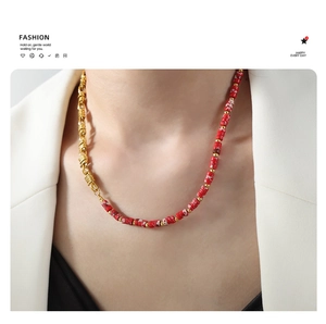 Detail of a luxury half-gold chain and red-white pattern stone necklace on a model