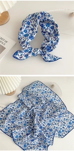 Detail of blue floral silk square scarf tied in a bow and flat layout on white background