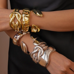 Close-up of chunky gold and silver bangles with geometric folds and high-polish finish