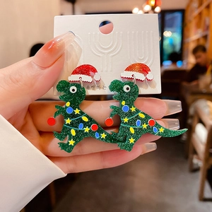 Macro shot of a Christmas dinosaur earring with glitter acrylic and a red Santa hat