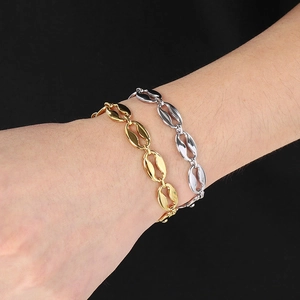 Detail of coffee bean link bracelets in gold and silver finish on a model wrist