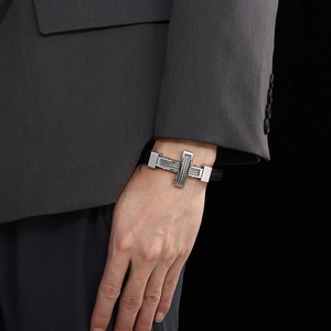 Close-up of men's leather bracelet with steel cross on a suit-wearing model wrist