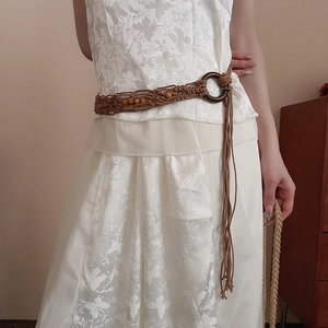 Close-up of handmade woven waist chain with wooden buckle and decorative beads