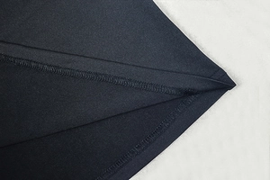 Gros plan du tissu de la robe noire montrant la couture double et la texture de la matière