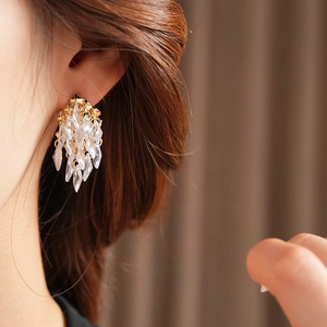 Détail de boucles d'oreilles pendantes dorées avec zircons portées par un modèle