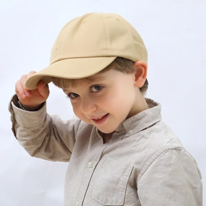 Close-up of khaki cotton baseball cap for kids worn by a model in a minimalist style