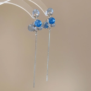 Macro shot of blue resin spheres and long silver snake chain tassels on elegant earrings