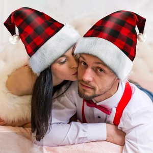 Close-up of red and black buffalo plaid Christmas hats with white faux fur and plush balls